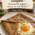 Une galette bretonne complète garnie de jambon, emmental et œuf sur une assiette, prête à être déguster.